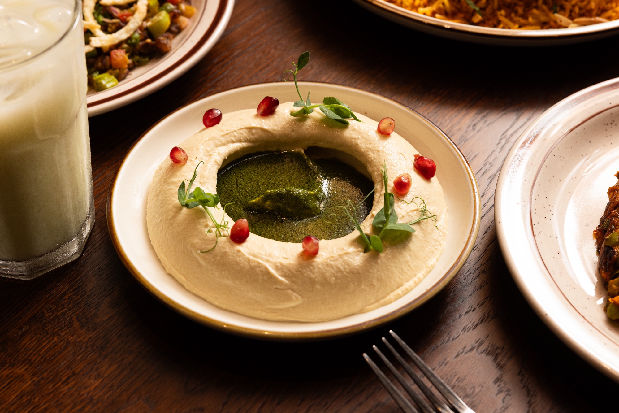 Hummus finished with green herb oil and pomegranate at Yemenat